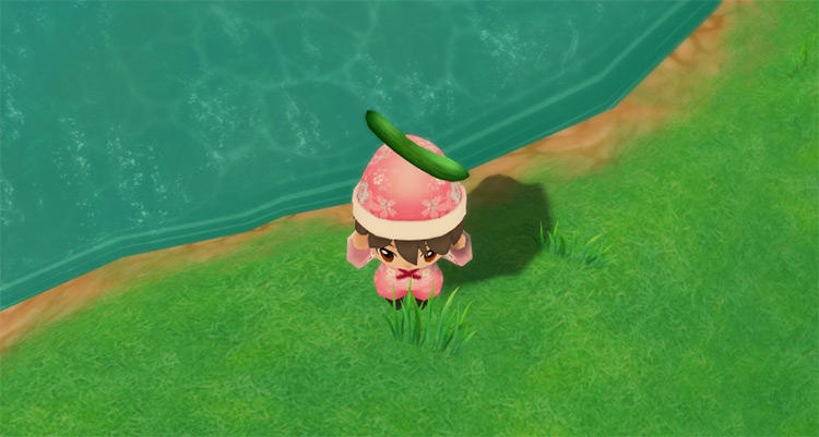 The farmer stands next to Kappa’s Lake while holding a Cucumber. / Story of Seasons: Friends of Mineral Town